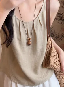 Detailed view of an ethnic wooden bear pendant necklace with leather cord on a linen top