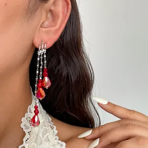 Gros plan de boucles d'oreilles à pampilles avec gouttes de verre rouges et clous