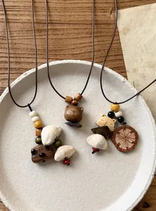 Detail view of ethnic wooden necklaces with cute animal-shaped pendants on ceramic plate