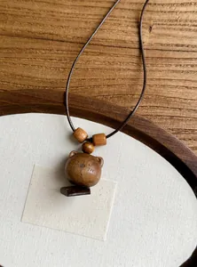 Macro view of a handcrafted wooden bear pendant on a durable brown leather cord