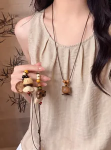 Detail view of handcrafted wooden animal pendants on long leather beaded necklaces