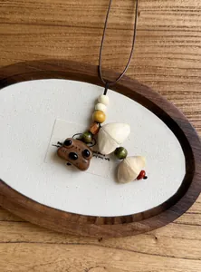 Close-up of ethnic style necklace featuring wooden beads and a handcrafted animal pendant