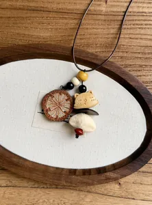 Detail of handmade ethnic wooden pendant necklace featuring a cat charm and earthy beads