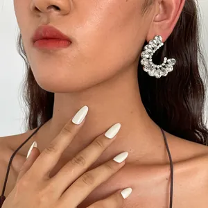 Gedetailleerde close-up van fonkelende strass C-vormige geometrische oorbellen op een model