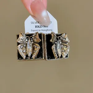 Detailed close-up of vintage butterfly earrings with black enamel and crystals.