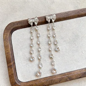 Detail of elegant silver bowknot tassel earrings with sparkling teardrop-shaped zircons.