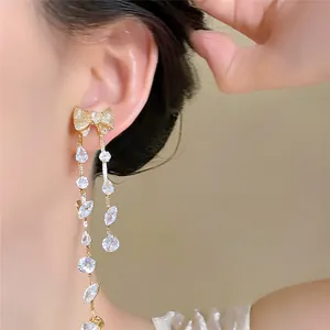 Elegant detail of zircon bow tassel earrings on model's ear, showing sparkling texture.