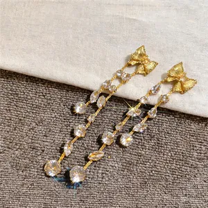 Close-up of elegant gold bow tassel earrings with sparkly cubic zirconia