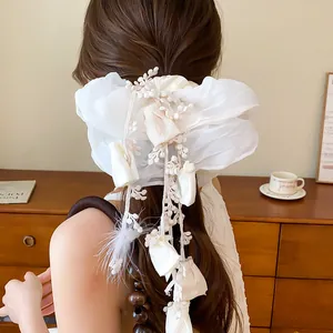 Detailed view of a white double-layer fabric scrunchie with tassel and flower accents