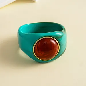 Makrodetail eines marmorierten Acryl-Armbands mit großem zentralem bernsteinfarbenem Harzstein