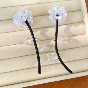 Close-up of glass crystal flower earrings with black cord stems in a jewelry box