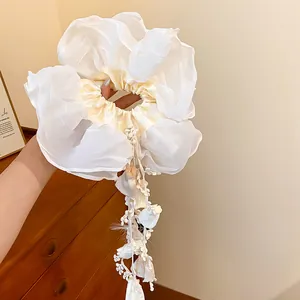 Detailed view of white double-layered scrunchie with delicate floral tassels and lace accents.