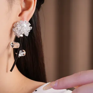 Macro view of crystal floral stud earrings with black leather cord tassel detail
