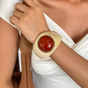 Nahaufnahme eines Vintage-Acryl-Armreifs mit bernsteinfarbenem Stein am Handgelenk.