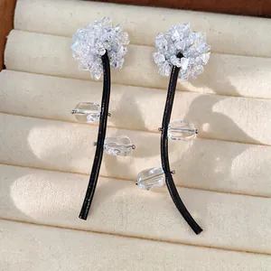Close-up of unique flower earrings with clear glass crystals and black leather cord stems