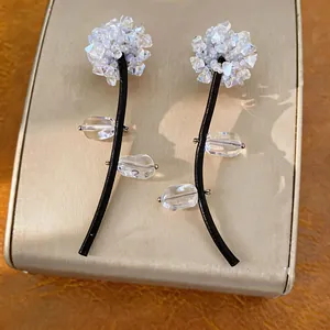Detailed view of handmade flower earrings with crystal beads and black leather stems.