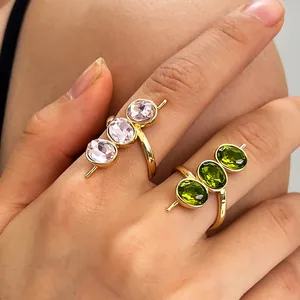 Detail goldener offener Ringe mit drei ovalen rosa und grünen Edelsteinen an der Hand