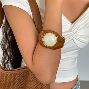 Nahaufnahme eines Retro-Bernstein-Acryl-Armreifs mit weißer Marmorierung am Arm