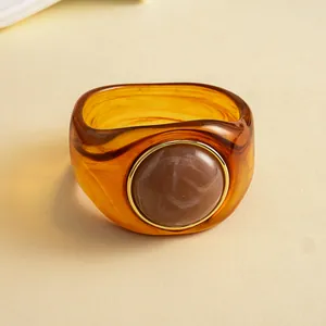Detailansicht eines vintage bernsteinfarbenen Acryl-Armreifs mit rundem Harz-Inlay
