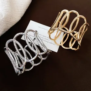 Detailansicht goldener und silberner hohler ovaler Manschettenarmbänder mit Textur