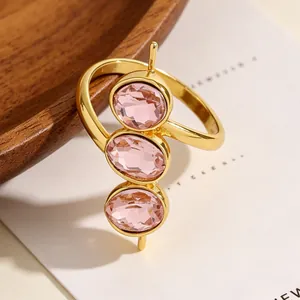 Nahaufnahme eines goldenen verstellbaren Rings mit drei ovalen rosa Zirkonia-Steinen