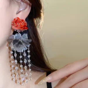 Close-up detail showing elegant red resin rose earring with long crystal bead tassels worn on ear