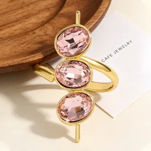 Nahaufnahme des verstellbaren goldfarbenen Rings mit drei ovalen rosa Zirkoniasteinen