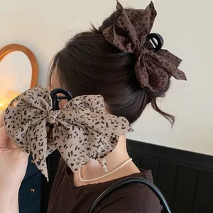 Detailansicht von Haarklammern mit Leopardendruck-Stoffschleife in Braun und Beige.