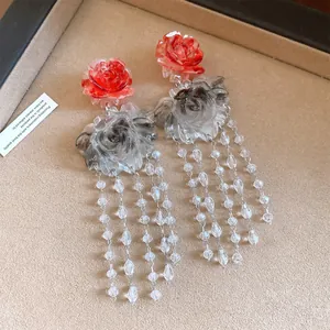 Detail of red and smoky grey resin flower earrings with long beaded tassels.