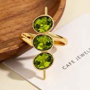 Detaillierte Makroansicht eines goldenen Rings mit drei vertikalen ovalen grünen Steinen.