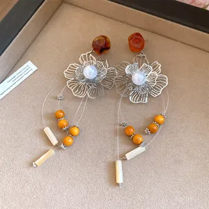 Detailed view of large silver needle resin flower tassel earrings on a velvet display tray