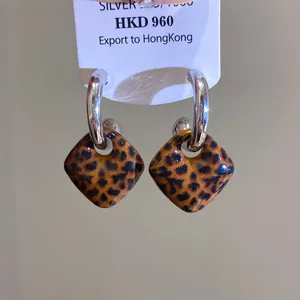 Nahaufnahme von Vintage-Creolen mit Leopardenmuster und Silberstiften auf Etikett