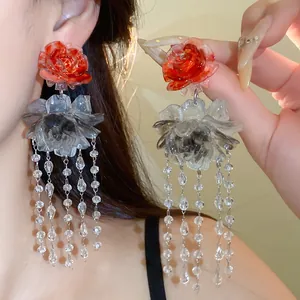Close-up of resin floral tassel earrings with ink-wash effect and crystal beads