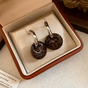Detailansicht von Retro-Ohrringen mit Leopardenmuster und Silbernadeln in einer Schmuckschatulle