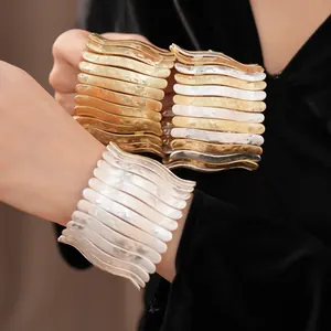Gros plan détaillé de bracelets manchettes élastiques plissés en métal texturé portés au poignet