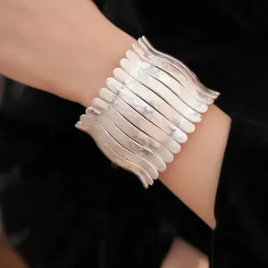 Gros plan détaillé d'un bracelet manchette en métal plissé argenté avec un design élastique.