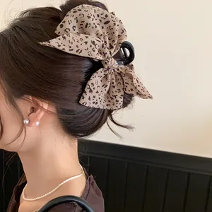 Detailansicht einer Haarklammer mit Leopardenmuster-Stoffschleife in braunem Haarknoten