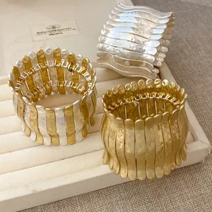 Détail de bracelets élastiques plissés métalliques aux finitions or et argent