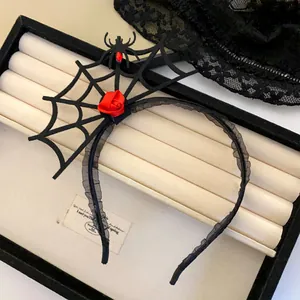Detailaufnahme eines schwarzen Spinnennetz-Stirnbands mit einer roten Rose und Spitze