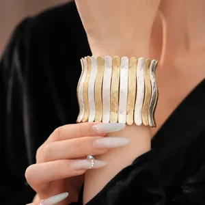 Gros plan détaillé d'un bracelet manchette en métal plissé bicolore martelé au poignet