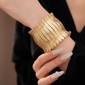Vue détaillée d'un large bracelet manchette doré avec un design texturé plissé élégant