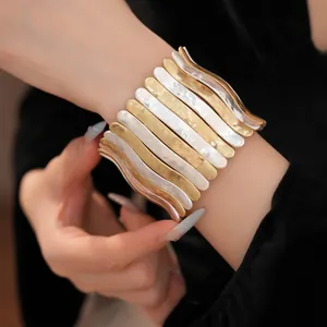 Gros plan montrant la texture d'un large bracelet élastique ondulé doré et argenté