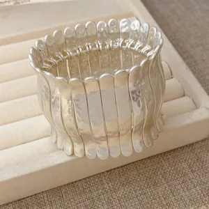 Détail des lamelles métalliques plissées argentées sur un bracelet élastique chic