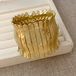 Gros plan sur un bracelet métallique plissé doré avec une texture martelée élégante