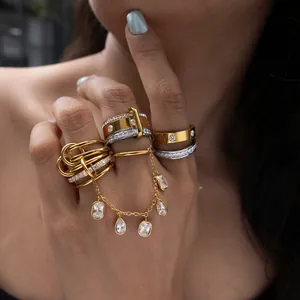 Elegante Nahaufnahme von gestapelten Edelstahlringen in Gold und Silber mit Kristallanhängern