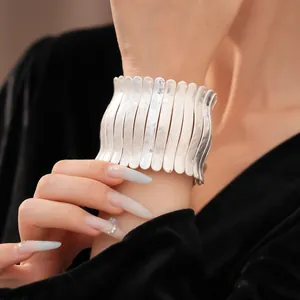 Bracelet manchette élégant en métal argenté avec texture plissée sur modèle