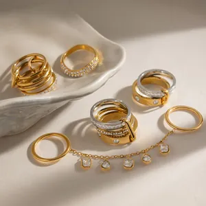 Detailansicht gestapelter Gold- und Silberringe mit Kristallanhängern und Kettendesign