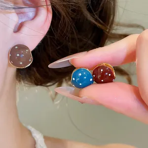 Close-up of vintage polka dot enamel earrings in brown, blue and red colors.