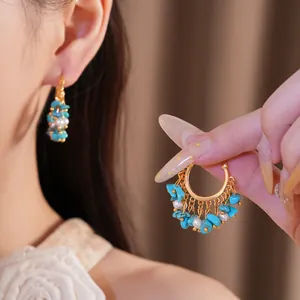 Primo piano di orecchini vintage placcati in oro con pietre turchesi e perle
