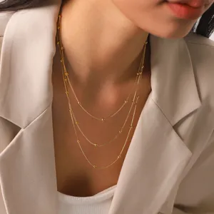 Close-up of elegant triple-layered gold bead necklace on a model wearing a blazer